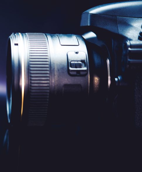 Digital Camera and the Photography Concept Photo. Dark Blue Color Grading with Little of Light. Camera Side View.